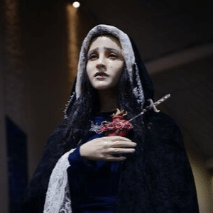 Foto de Nossa Senhora das Dores com um manto escuro e uma pequena espada transpassando seu coração