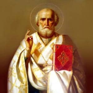 Imagem de São Nicolau de Mira com vestes brancas e detalhes em dourado. Segurando um livro vermelho na mão esquerda