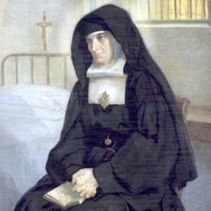 Imagem de Santa Rafaela Maria vestida como religiosa. Está sentada numa cama de enfermaria nde se vê, ao fundo, um crucifixo