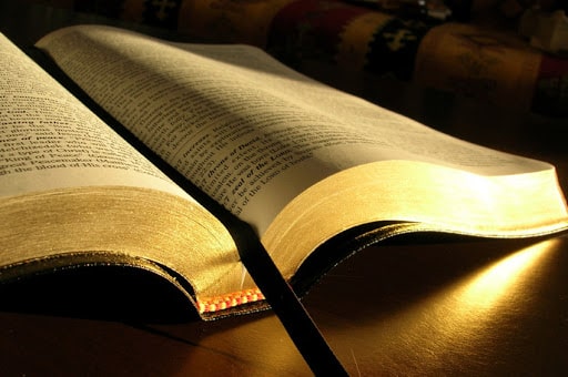 Bíblia aberta sendo iluminada por uma luz dourada
