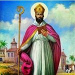 Imagem de São Cipriano cm vestes episcopais branco e rosa. Segura um báculo(cajado) na mão direita e uma bíblia na mão esquerda. Está com a mitra na cabeça. Ao fundo vê-se uma paisagem africana